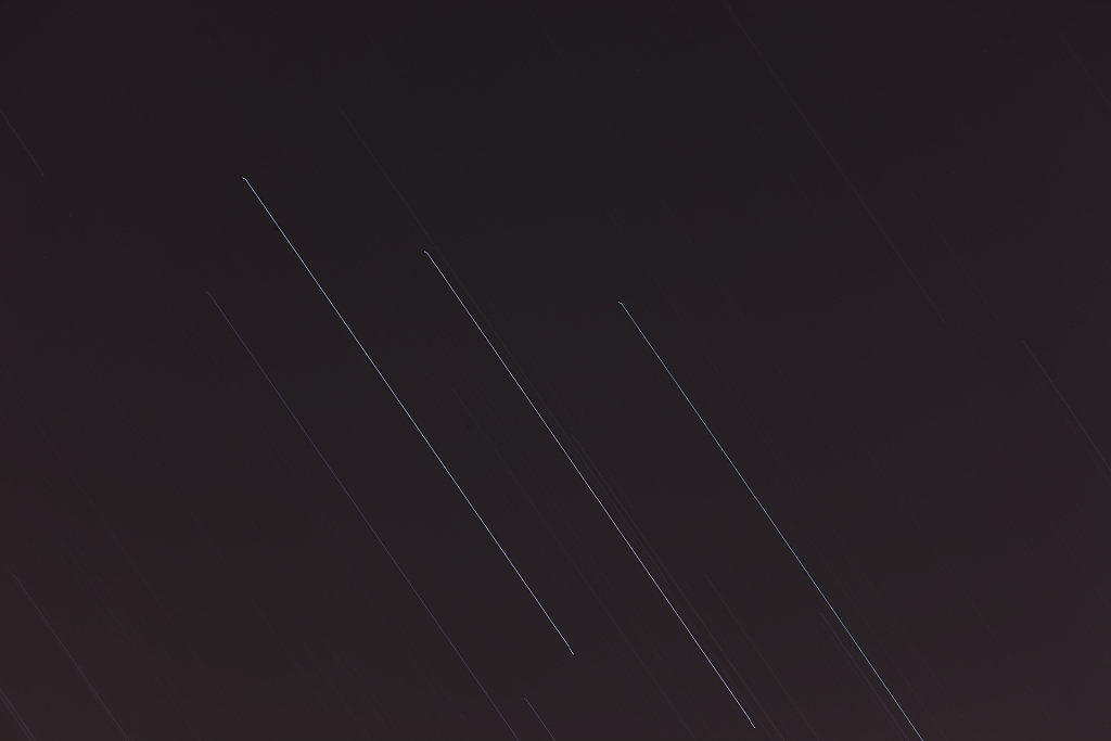 The stars of Orion's belt streak across the night sky.