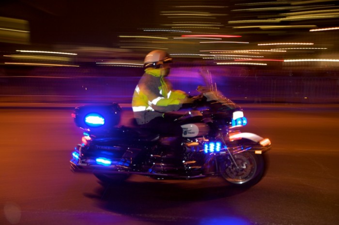 A police officer rides by on a motorcycle before the Mystic Stripers roll their Mardi Gras parade along Church Street in downtown Mobile, Ala., Thursday night, Feb. 11, 2010.