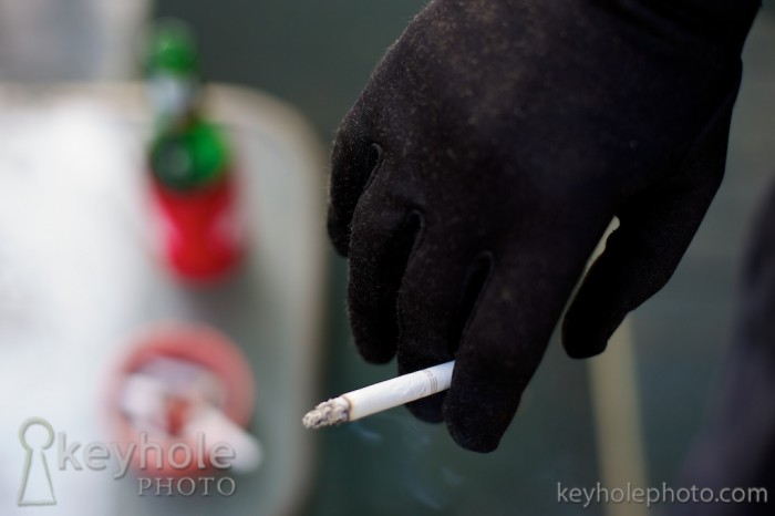 A gloved hand holds a cigarette in Mobile, Ala., Sunday, March 28, 2010.