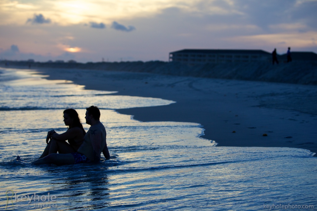 Couple Sits on Beach at Sunset