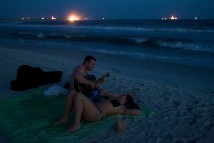 Craig Hare serenades Maria Nelson as night falls on the beach at Dauphin Island, Ala., Wednesday evening, July 7, 2010, after getting engaged earlier in the day. "This is the first day of the rest of our lives together, and it's great," Hare said. The town's beach now has a sand berm above the surf, aimed at preventing oil from the Deepwater Horizon oil spill from making it very far onto the beach.