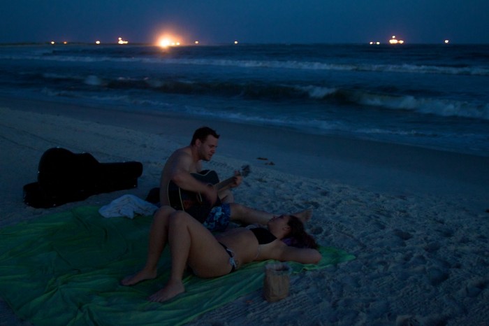 Craig Hare serenades Maria Nelson as night falls on the beach at Dauphin Island, Ala., Wednesday evening, July 7, 2010, after getting engaged earlier in the day. "This is the first day of the rest of our lives together, and it's great," Hare said. The town's beach now has a sand berm above the surf, aimed at preventing oil from the Deepwater Horizon oil spill from making it very far onto the beach.