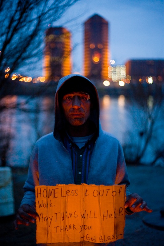 Harry Shoup shows off a sign he uses for panhandling while hanging out at a homeless camp on the banks of the Ohio River in Cincinnati, Ohio, Sunday evening, March 5, 2006, with the Covington, Ky., skyline in the background. Shoup said he has trouble getting a decent job because he said he spent 25 years in jail for an accessory to murder charge.