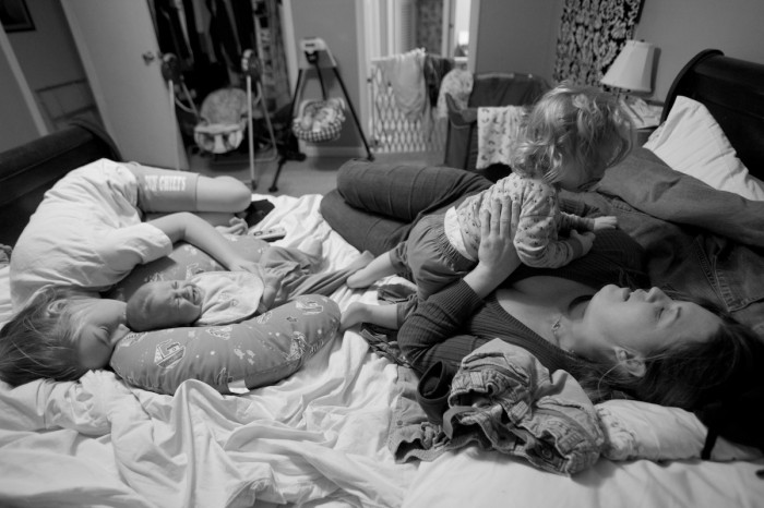 A mother and her daughter comfort her toddler and twins.