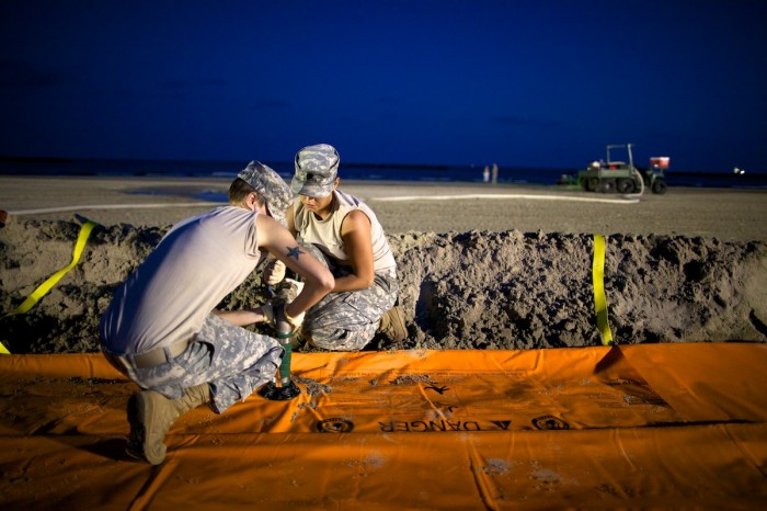 Members of the National Guard work into the evening hours to fill Tiger Dams with water on the beach of Grand Isle, La., Monday, May 31, 2010. Though oil reached the town's beach earlier in May, nearly a month after the Deepwater Horizon oil spill began, the dams were being built to keep any future oil washing ashore in the sand where it can dealt with more easily.